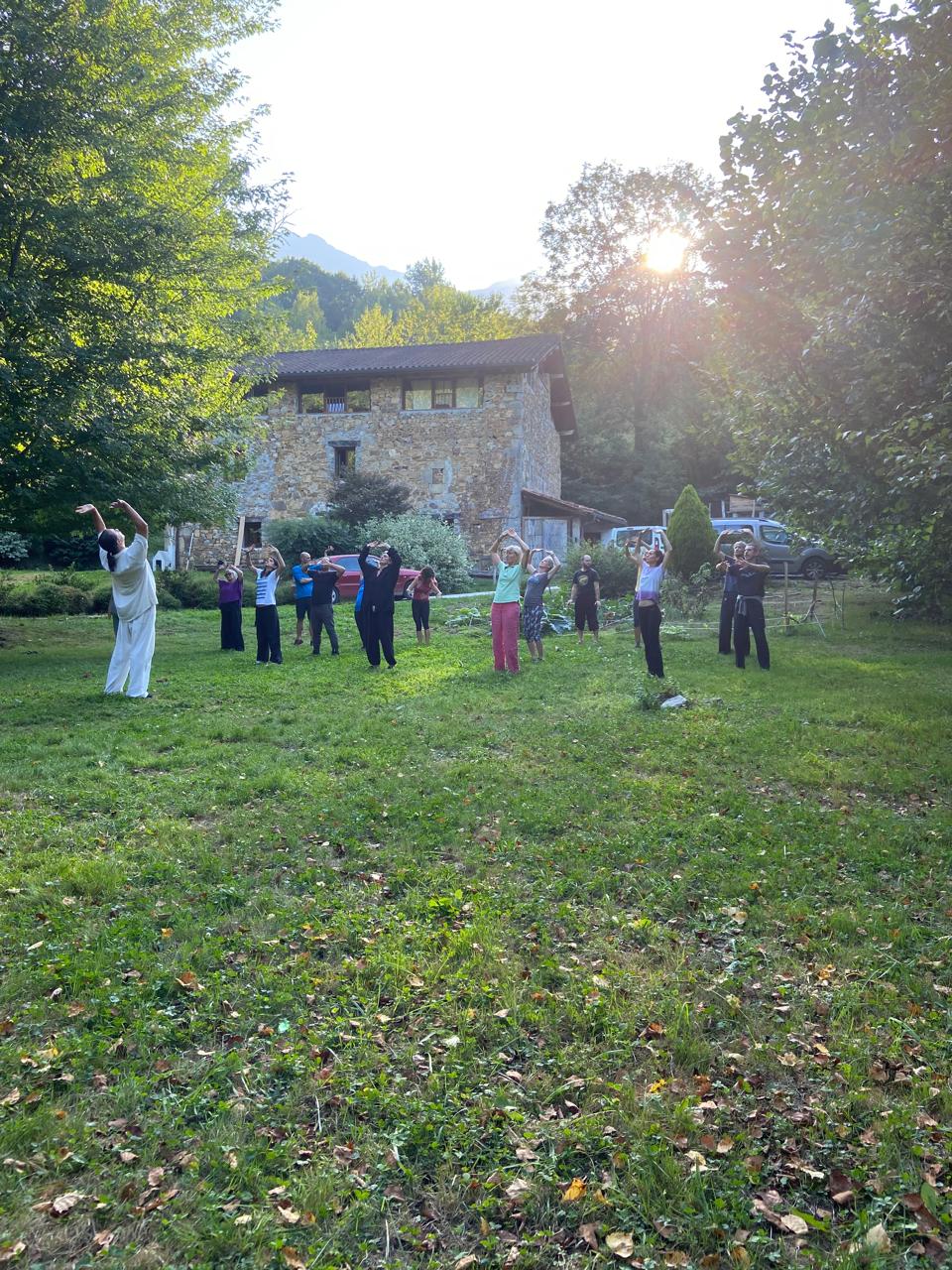 Grupo em prática ao entardecer frente à casa de pedra